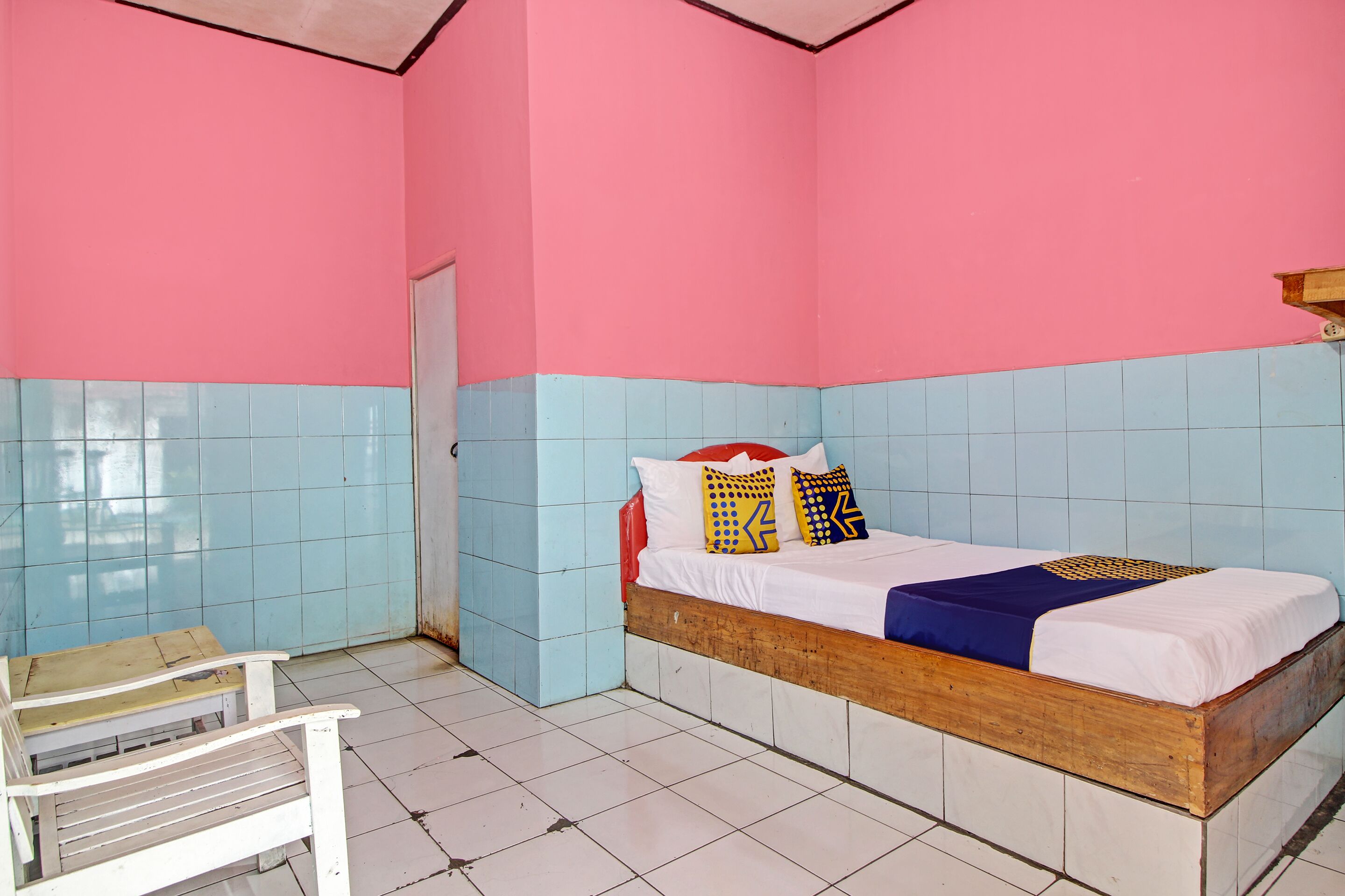 A room with a bed, a bench, and a door.
