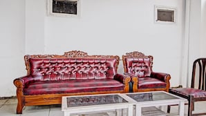 A red leather sofa with a glass coffee table in a room with white walls and tiled flooring. - Hotel O 4 Saudara Hotel (Ambarawa)
