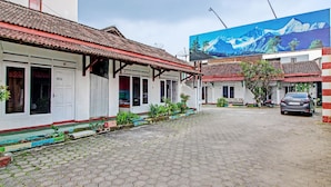 A street with traditional buildings, a parked car, and a large billboard. - Hotel O 4 Saudara Hotel (Ambarawa)