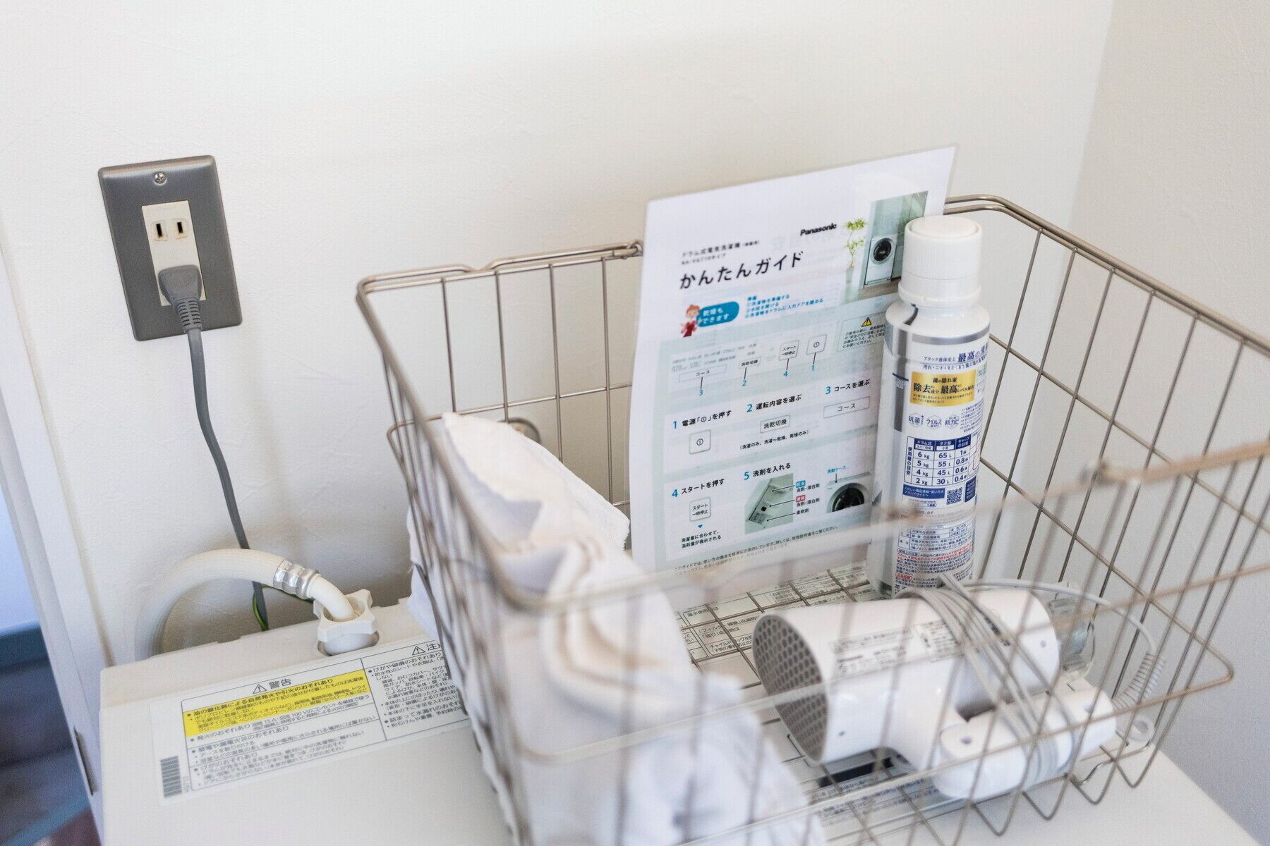 A small metal basket containing a white appliance, a bottle, and a paper with Japanese text.
