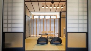 A traditional Japanese room with tatami flooring, a low table, two black cushions, and a sliding shoji screen. - Enyu No Yado Dogo (Matsuyama)