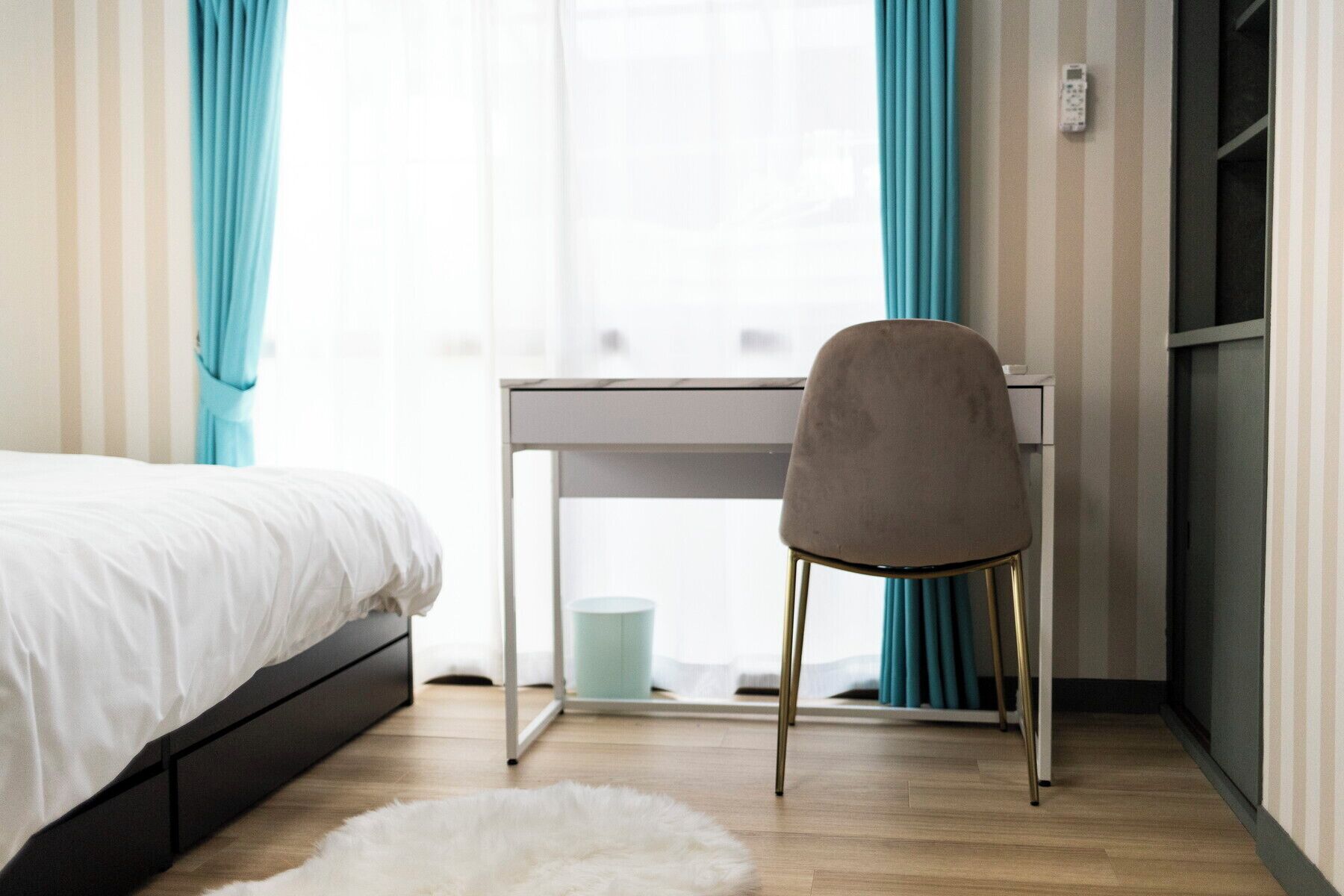 A bedroom with a bed, a desk, and a chair.