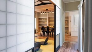 A room with tatami flooring, a sliding door, and a view into a dining area with a table and chairs. - Enyu No Yado Dogo (Matsuyama)