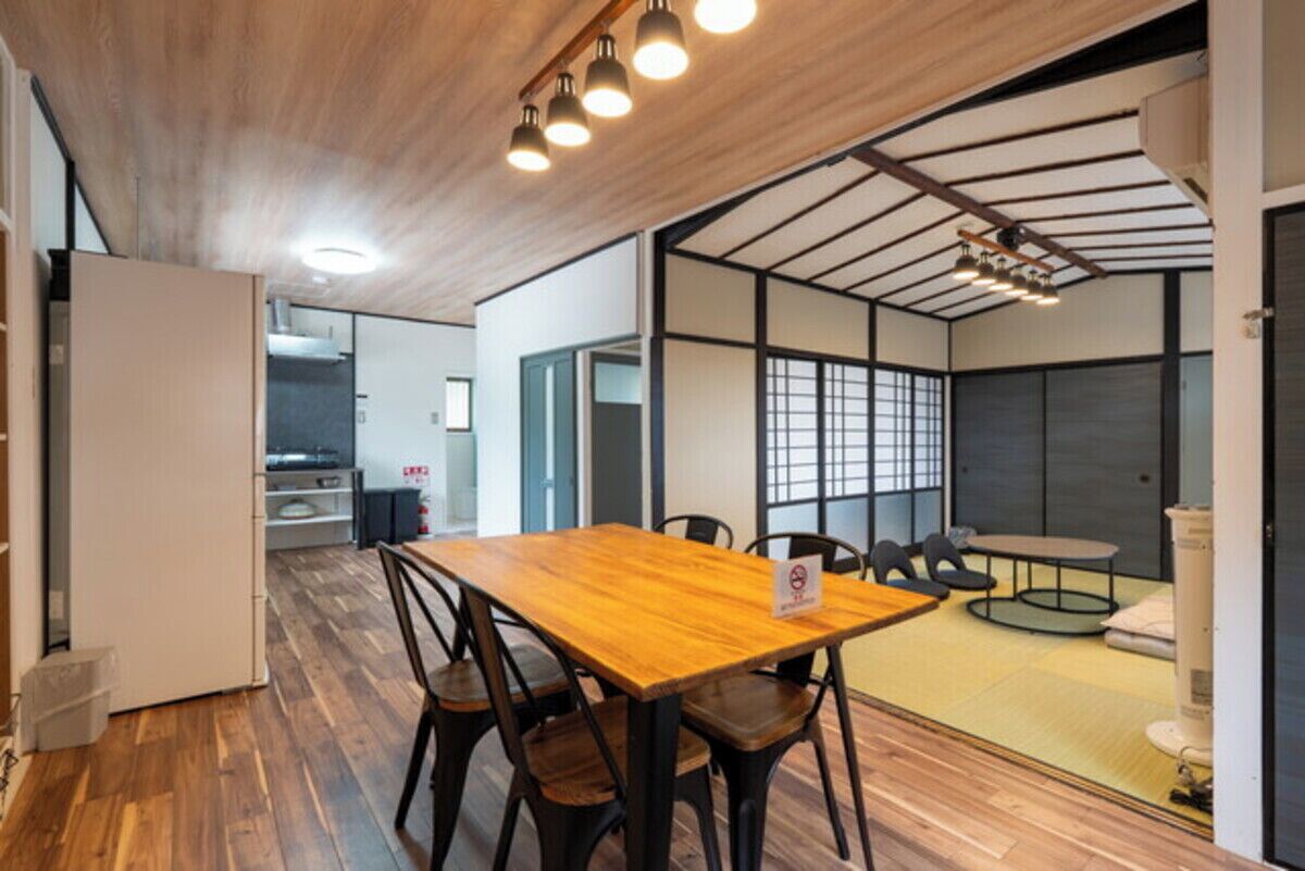 Un interior moderno con una mesa de comedor de madera, sillas y una pequeña mesa redonda con cojines.