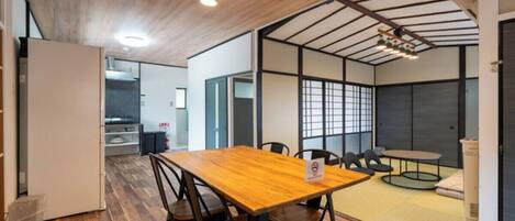 Un interior moderno con una mesa de comedor de madera, sillas y una pequeña mesa redonda con cojines.