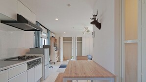 A modern kitchen with a central island, built-in appliances, and a dining area with a wooden table and bench.