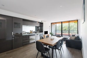 Une cuisine moderne avec un coin repas, de grandes fenêtres et une vue sur la verdure.