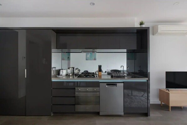 A modern kitchen with a built-in oven, dishwasher, and a large flat-screen TV.
