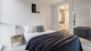 A modern bedroom with a bed, bedside table, and a large mirror.