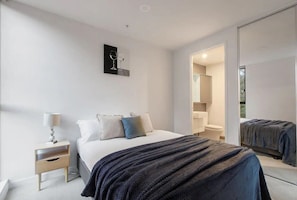 Una camera da letto moderna con un letto, un comodino e un grande specchio.