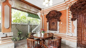 Une table à manger traditionnelle en bois, entourée de chaises, et agrémentée de décorations murales élaborées et d’un escalier.