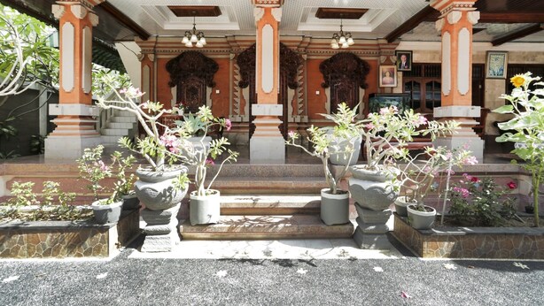 Une entrée de bâtiment de style traditionnel, avec des colonnes en pierre, des marches et des plantes en pot.