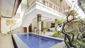 Une piscine avec une terrasse carrelée, un escalier et une voiture garée à proximité.