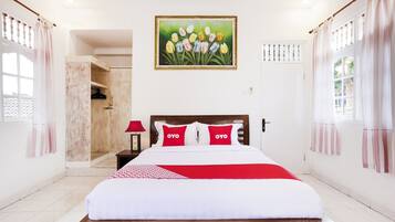 A neatly arranged hotel room with a bed, a nightstand, a painting of tulips, and a door leading to a bathroom.