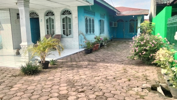 Un patio con pavimento hexagonal, plantas en macetas y un edificio azul con ventanas arqueadas.
