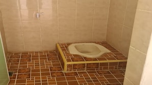 Un baño pequeño con inodoro, ducha y suelo de baldosas.