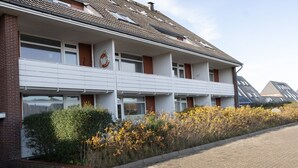 A multi-story building with a flat roof, large windows, and a brick facade. - Die Wohnung Treibholz mit Balkon Liegt in Einer Sehr Ruhigen Lage in Hörnum (Hörnum (Sylt))