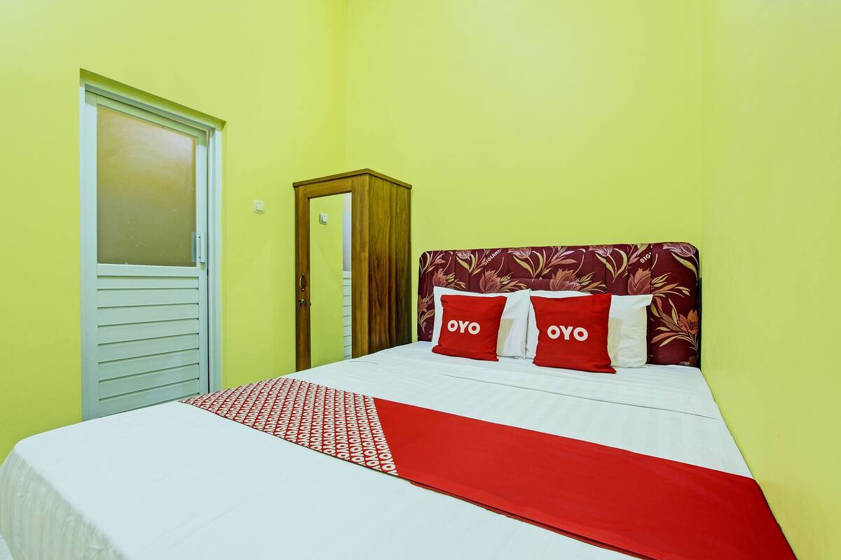 Une chambre d’hôtel avec un lit, une armoire et une porte.