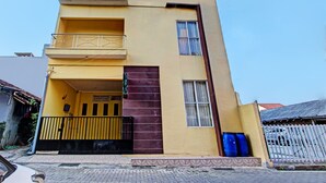 A multi-story building with a yellow facade, a balcony on the second floor, and a gated entrance. - Hotel O Umi Rahayu Guesthouse (Semarang)
