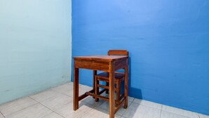 A wooden chair and table against a blue wall, with tiled flooring. - Hotel O Gioba Kost Syariah (Wirosari)