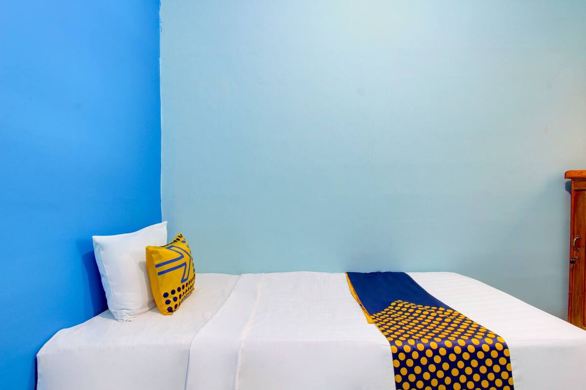 A bed with white bedding, a blue wall, and a wooden door.