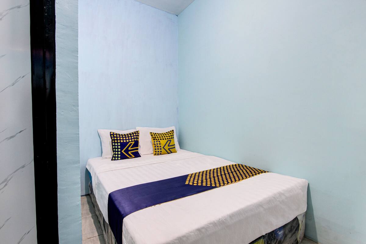 A bedroom with a bed, pillows, and a blanket.