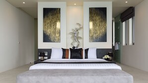 Un dormitorio amplio y moderno con una cama grande, dos obras de arte colgadas en la pared, una escultura decorativa y un box de ducha de vidrio.
