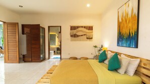 A bedroom with a wooden bed, a large painting, and a view of the outdoors. - Casa Sweet Lips by Betterplace (Canggu)