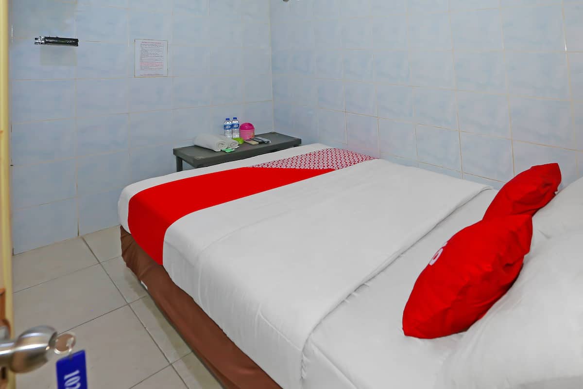 Ein Hotelzimmer mit Bett, Nachttisch und einer Fliesenwand.