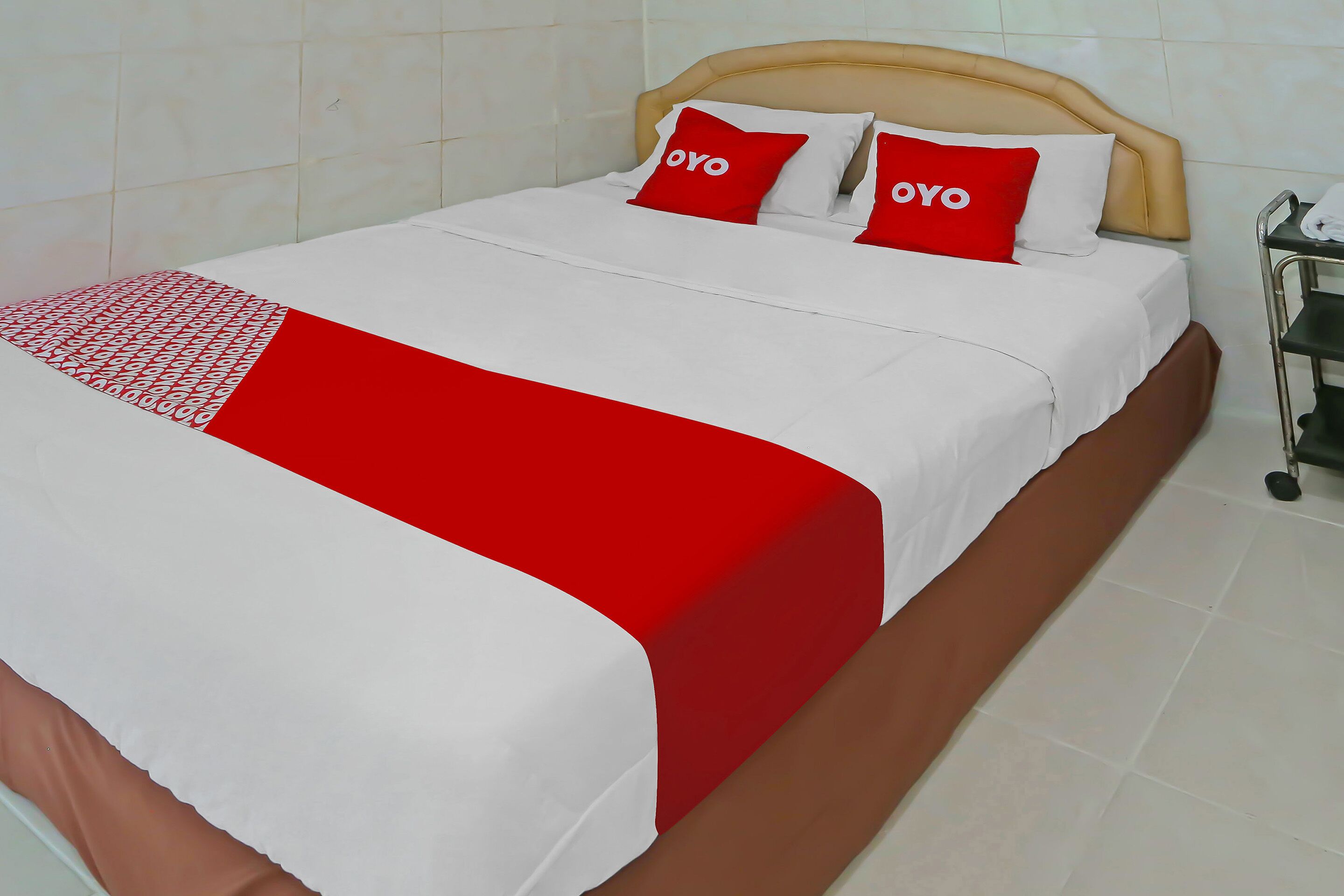A neatly made bed with a red and white bedspread and two pillows with the word "OYO" on them.