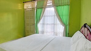 Een kamer met een bed, groene gordijnen en een deur.