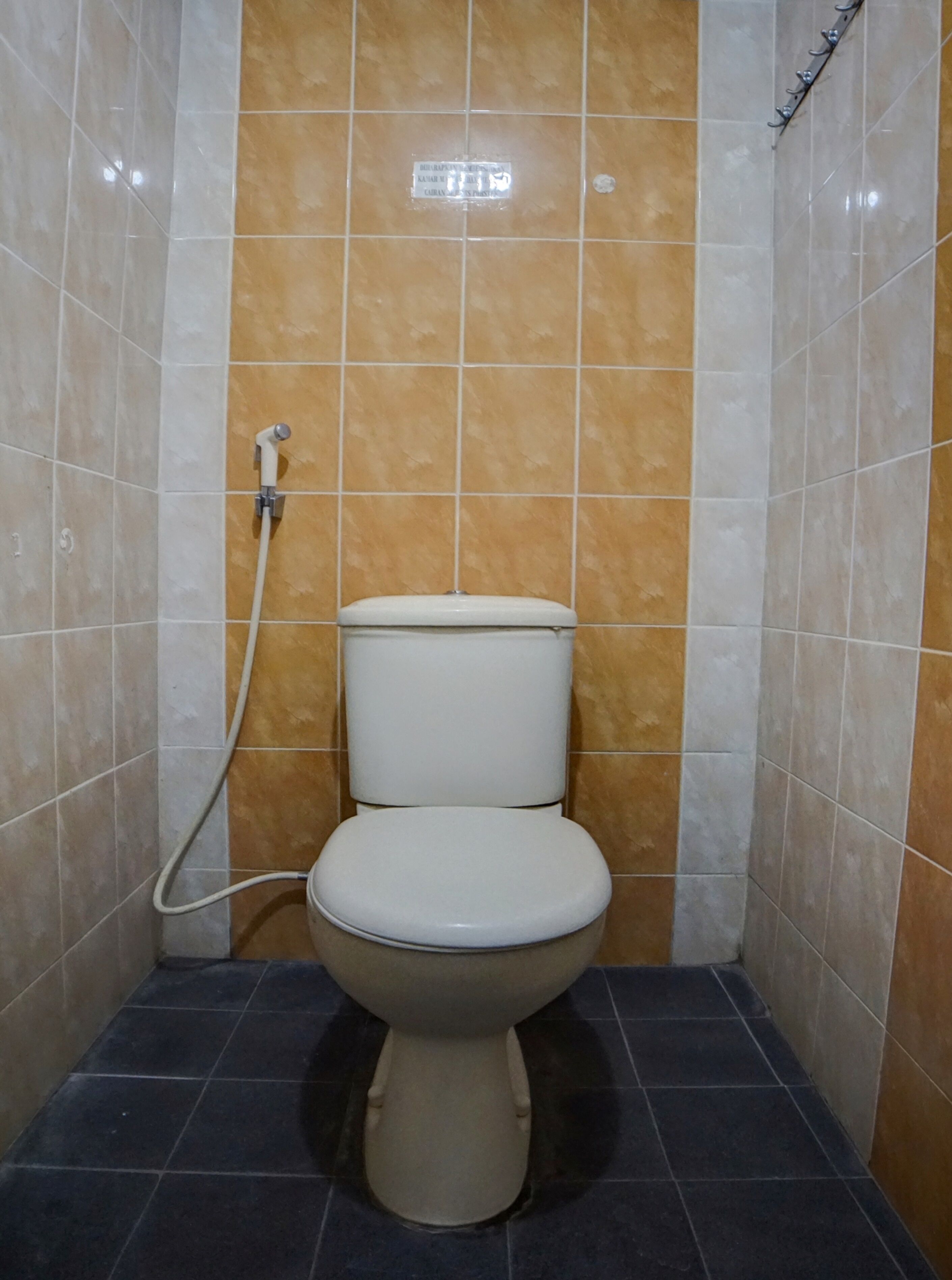 Un baño con inodoro, ducha y paredes de azulejos.