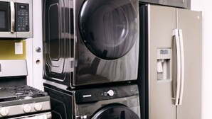 Une cuisine compacte équipée d’un four à micro-ondes, d’un four double, d’un réfrigérateur et d’un lave-linge placés les uns au-dessus des autres.