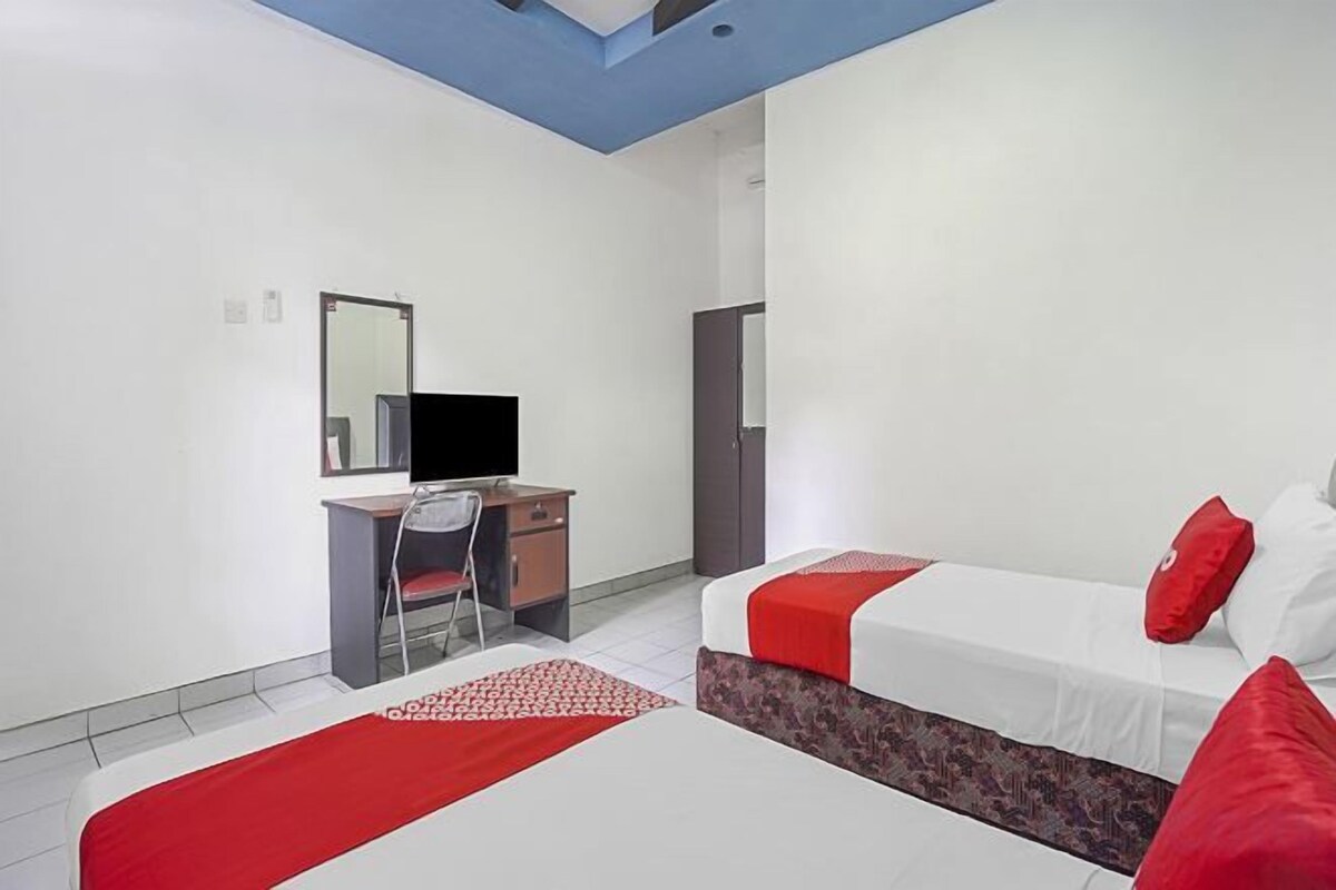 A hotel room with two beds, a desk, and a TV.