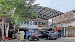 Un bâtiment doté d’une entrée couverte, une voiture garée et un camion bleu.