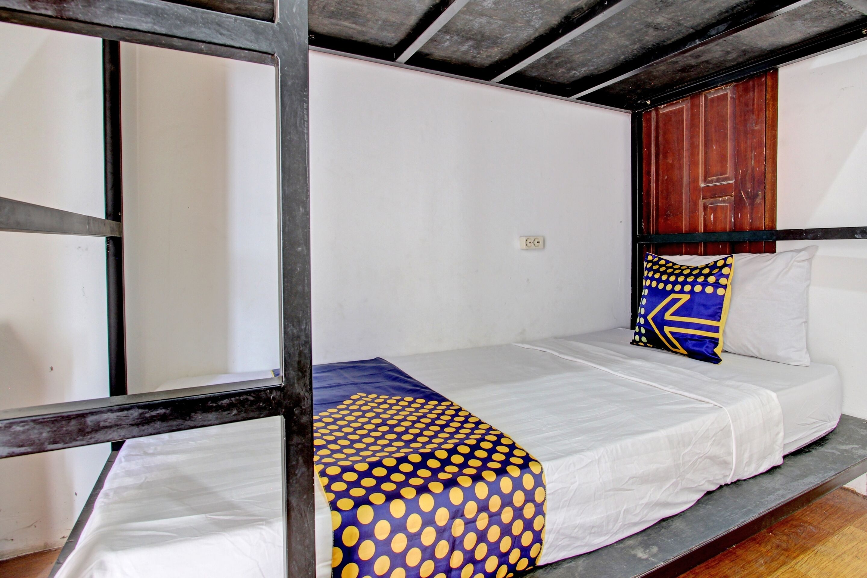 A single bed with a white mattress and a blue and yellow polka dot blanket.