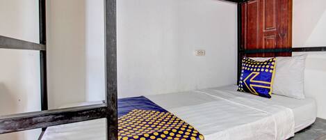 A single bed with a white mattress and a blue and yellow polka dot blanket.