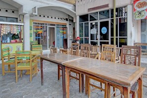 Un espace extérieur aménagé avec des tables et des chaises en bois, un stand de restauration et l’entrée d’un restaurant.