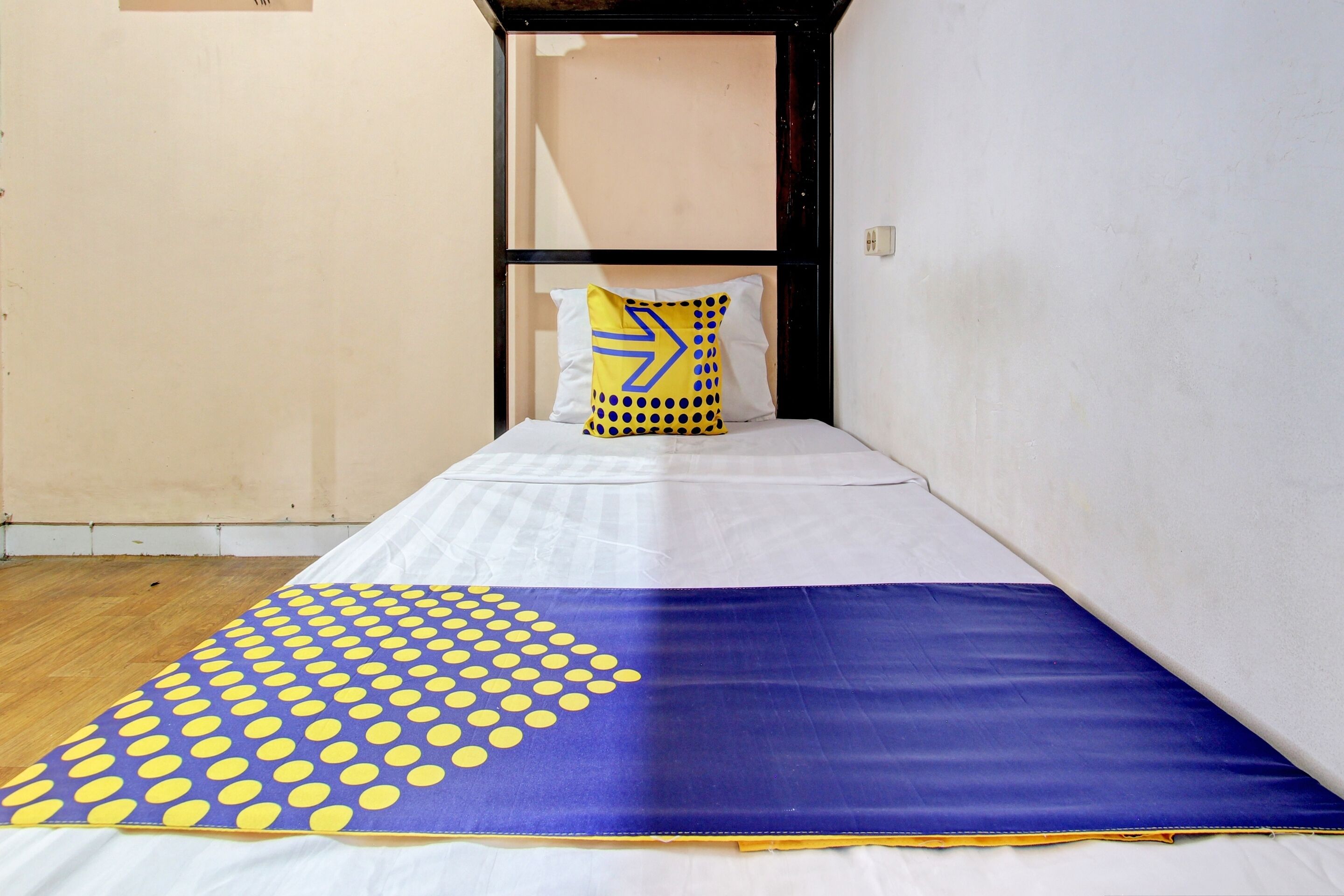 A narrow room with a bed, a pillow with a geometric design, and a patterned blanket.