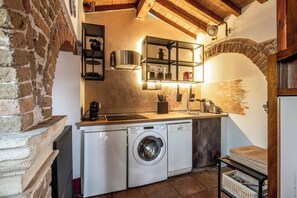 Una cucina compatta con lavatrice, lavello e piano cottura.
