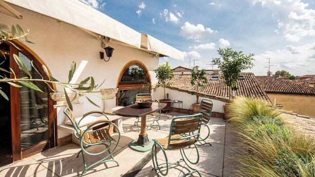 An outdoor patio with a table and chairs, a potted plant, and a view of the river. - Dimora Del Filosofo (Verona)