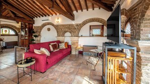 A cozy living room with a red sofa, a TV, and a fireplace. - Dimora Del Filosofo (Verona)