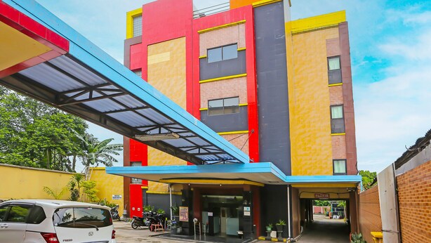 A multi-story building with a modern design, featuring a mix of red, yellow, and blue colors. - Hotel O Sion Holiday (South Tangerang)
