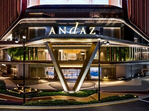 Et moderne hotel med et markant 'ANDAZ'-skilt, et centralt atrium og et anlagt udendørs område.