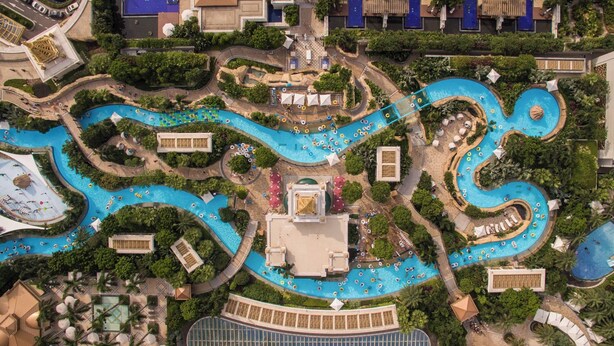An aerial view of a resort with multiple interconnected swimming pools, walkways, and lush greenery. - Andaz Macau  (Cotai)