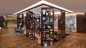 A modern interior with a wooden staircase, a glass railing, and a variety of decorative items on shelves. - Andaz Macau  (Cotai)