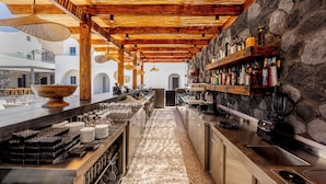 Una cocina moderna con pared de piedra, techo de madera y una zona de bar con diferentes botellas y vasos.