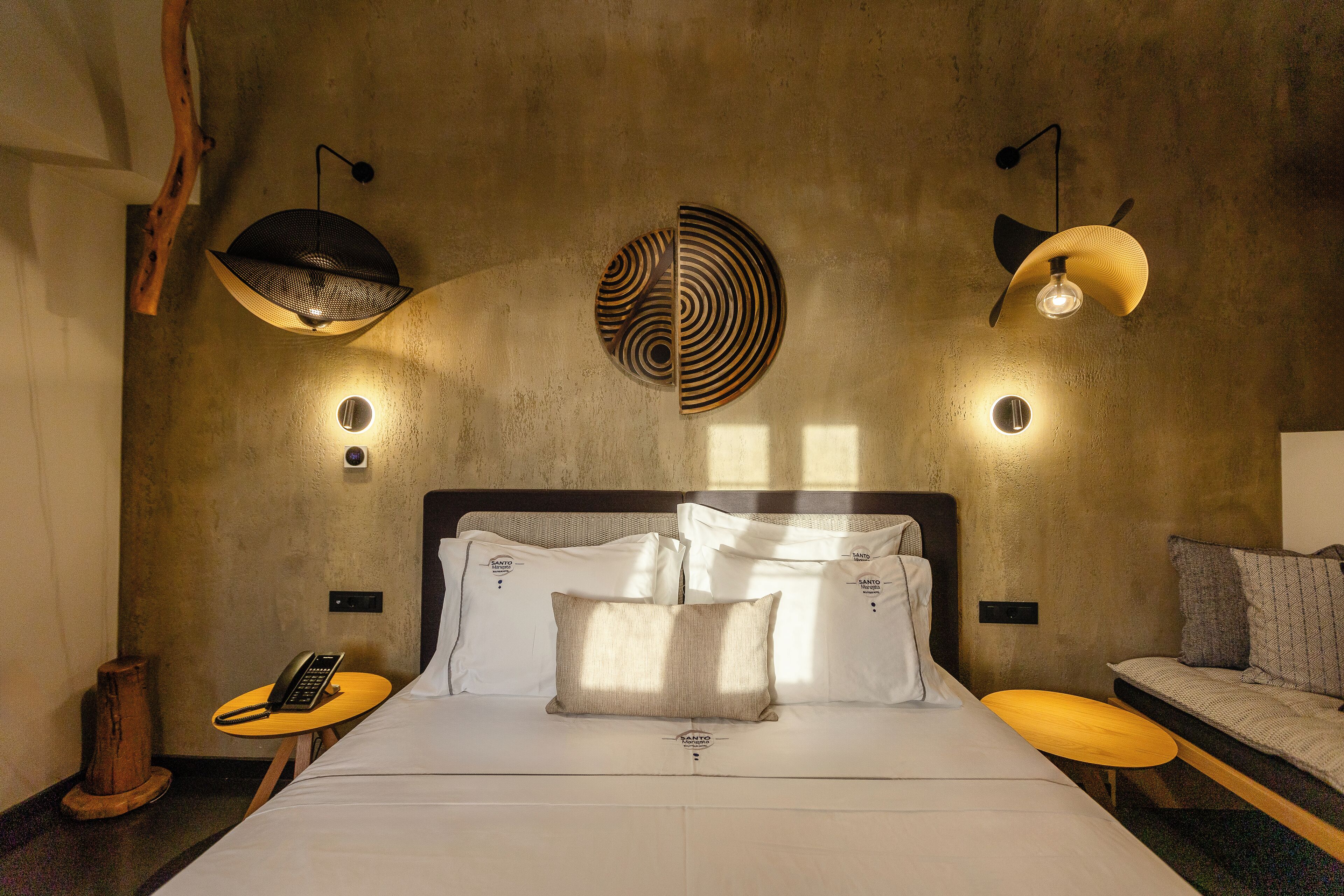 Een moderne hotelkamer met een groot bed, een klein tafeltje, een bank en een bijzonder kunstwerk aan de muur.