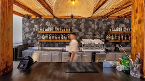Un área de bar con pared de piedra, techo de madera y estantes llenos de botellas de licor.