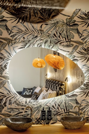 A bathroom with a large mirror, a sink, and two hanging lamps.